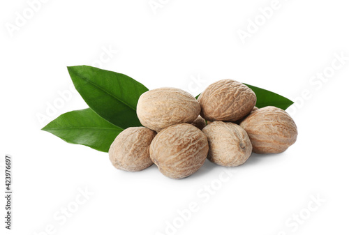 Nutmeg seeds with green leaves on white background