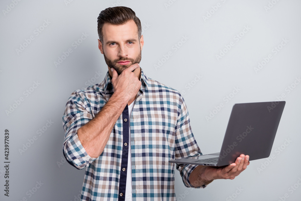 Portrait of attractive skilled content bearded guy holding in hand using laptop it isolated over gray pastel color background Portrait of attractive skilled content bearded guy holding in hand using laptop it isolated over gray pastel color background