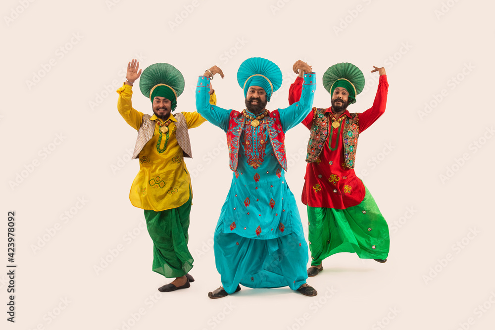 Naklejka premium Three Bhangra dancers performing a dance step with hand gestures. 