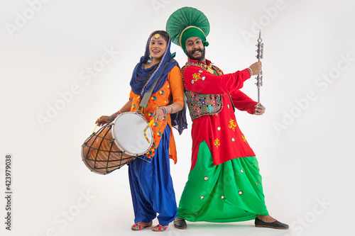 A Giddha dancer with a dhol and a Bhangra Dancer with Chimta representing folk dance.	