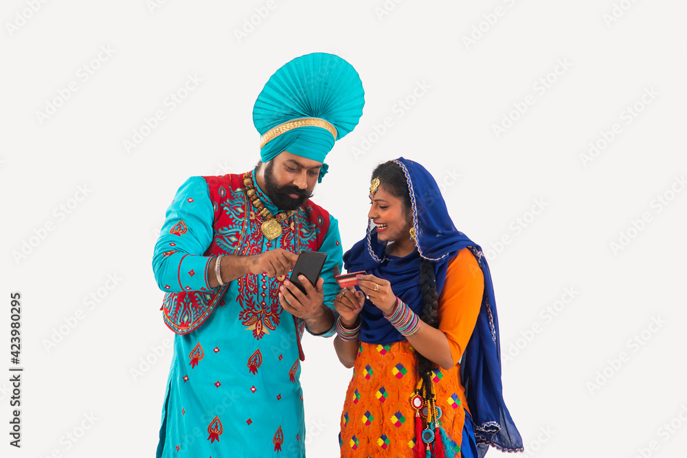 A Bhangra and A Giddha Dancer discussing bills having a mobile and credit card in hand.	