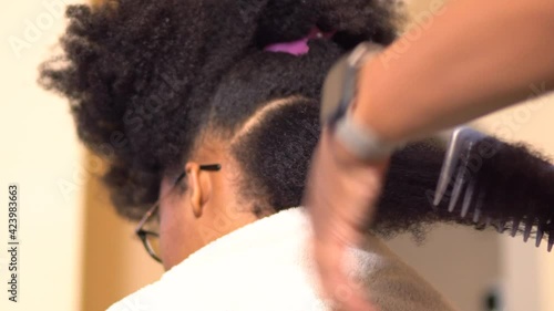 Mother combing and styling her teenage daughters beautiful hair at home