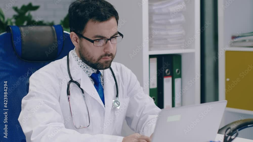 Young male doctor working on a laptop. Distance Online Learning. Young male doctor working on a laptop. Distance Online Learning.