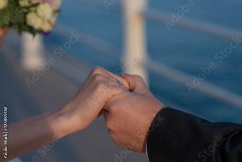 Man holding woman's hand in a romantic gesture, close-up on hands and engagement diamond ring, beautiful happy couple getting married, concept for a traditional commitment to family and life together