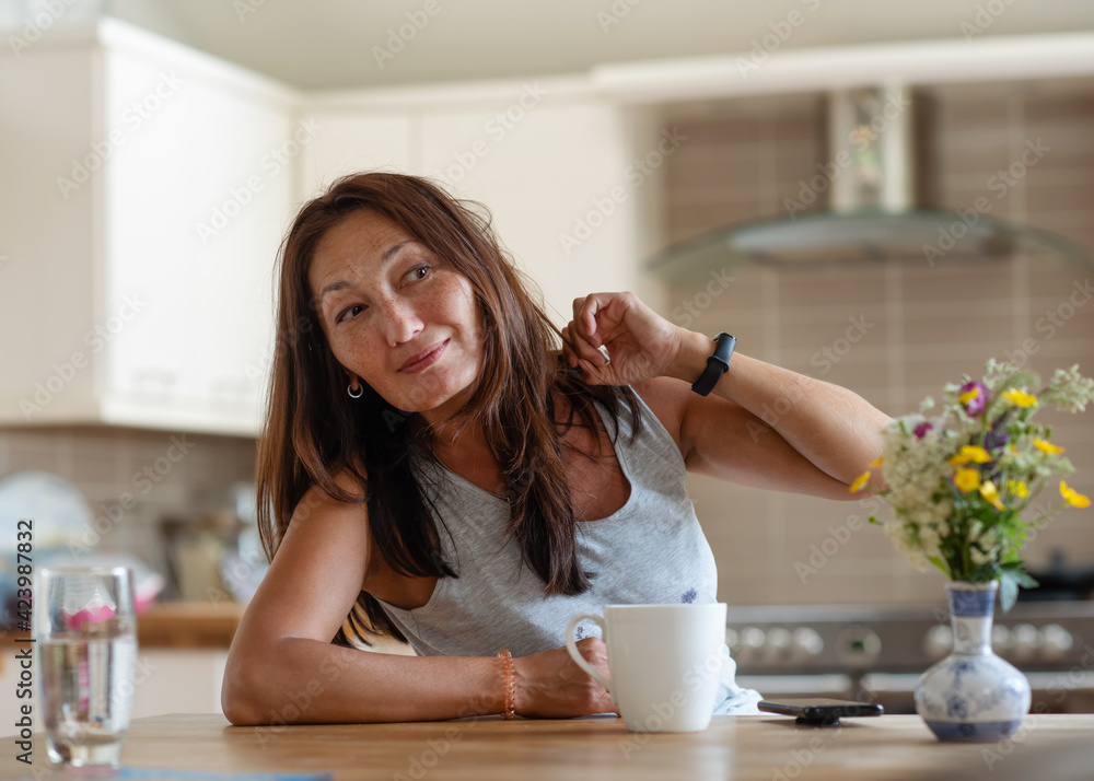 An Asian woman smiling and having breakfast in a kitchen An Asian woman smiling and having breakfast in a kitchen