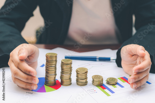 business woman hand keep coin increased coin stacking on growth graph and chart with calculator count money saving for financial and accounting concept.