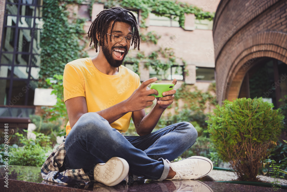Photo portrait of young student playing video games on cellphone wearing casual outfit glasses Photo portrait of young student playing video games on cellphone wearing casual outfit glasses