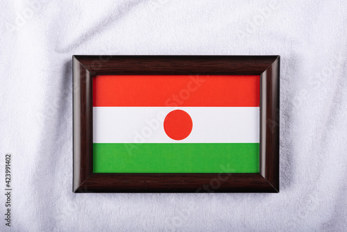 Niger flag in a realistic frame on white cloth background flat lay photo