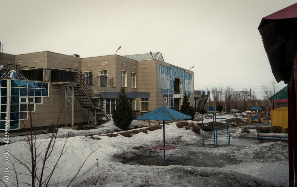 Naklejka premium Cityscape in early spring, March in a residential area - a kindergarten against the background of gray sky. Ust-Kamenogorsk (kazakhstan)