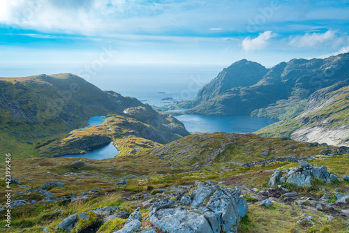 Mountains of Lofoten Island on a sunny arctic day. View from trail to Hermannsdalstinden peak. Hiking mountains of Lofoten, Norway, on a beautiful day of arctic summer. Seeing fjords from above. photo