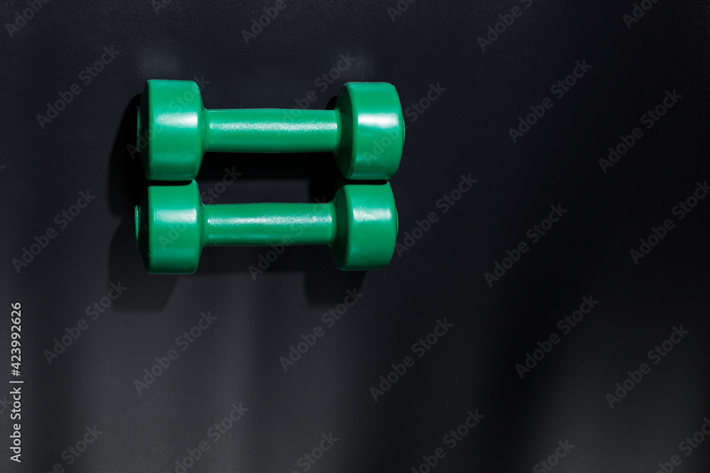 Greeen small dumbbells. Dumbbells for fitnes on black with copy space. Greeen small dumbbells. Dumbbells for fitnes on black with copy space.