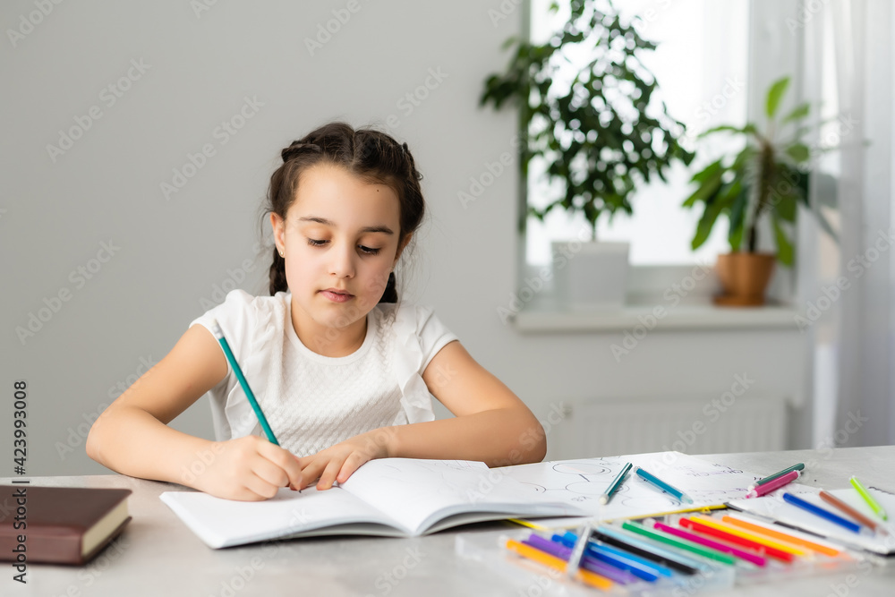 Cute little girl studying at home and smiling Cute little girl studying at home and smiling