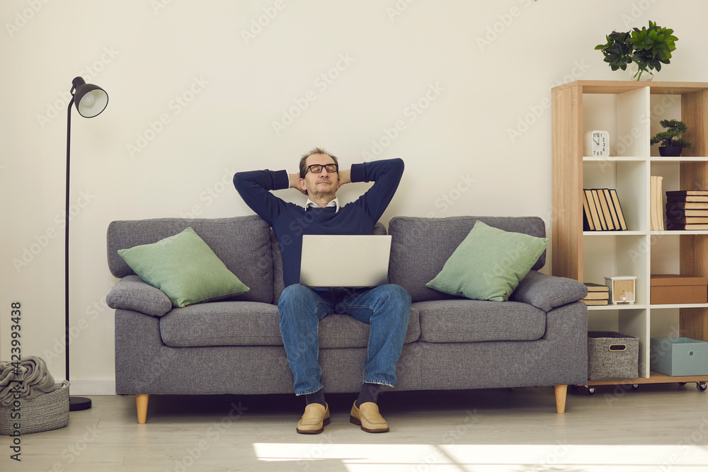 Calm mature man with eyes closed sleeping or napping relaxing on comfortable lounge couch with laptop device in cozy home enjoying lazy leisure lifestyle. Relaxation, laziness during short break