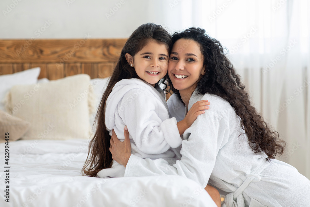 Cheerful mother and daughter hugging in bedroom, copy space Cheerful mother and daughter hugging in bedroom, copy space