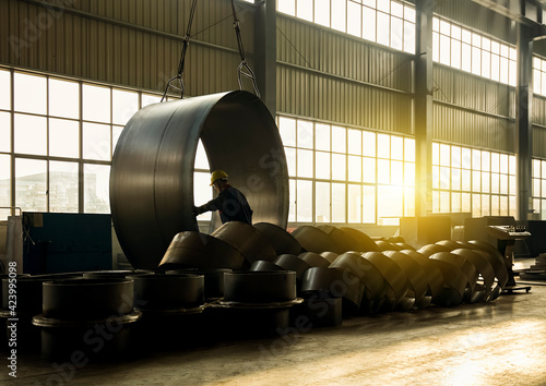 Slika na platnu Asian workers are at work in a factory, lifting large steel