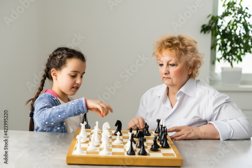 Grandmother and young girl playing chess together at home