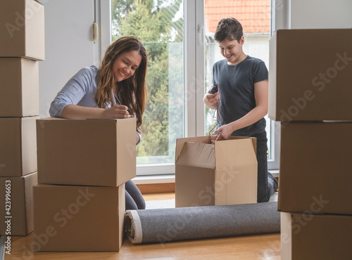 
Single mom with a teenage son controls a check list of things to move to new apartment.Brown cardboard boxes with copy space.Moving concept.