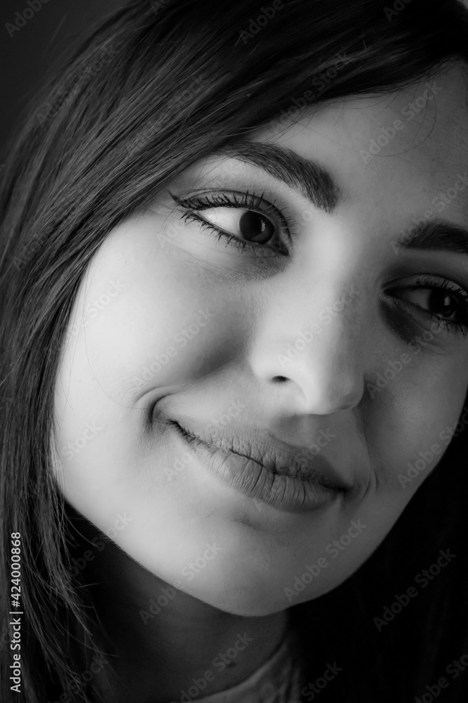 Close up black and white portrait of a beautiful young smiling woman with long dark hair Close up black and white portrait of a beautiful young smiling woman with long dark hair