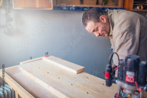 Senior carpenter manual worker working with chair on a piece of wood in workshop.