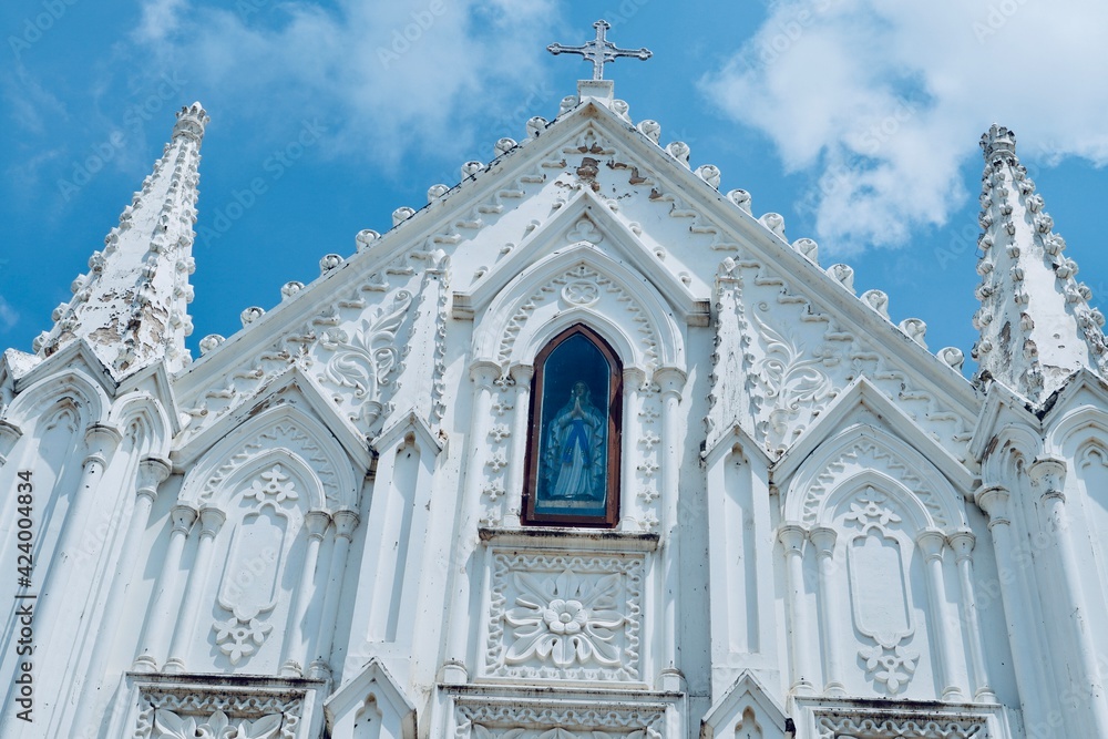 Fototapeta premium Basilica of Our Lady of Good Health, Sanctuary of St. Mary's shrine, Cathedral of St. Mary, facade of holy trinity. Roman Catholic Latin church tower against blue sky background in Velankanni.