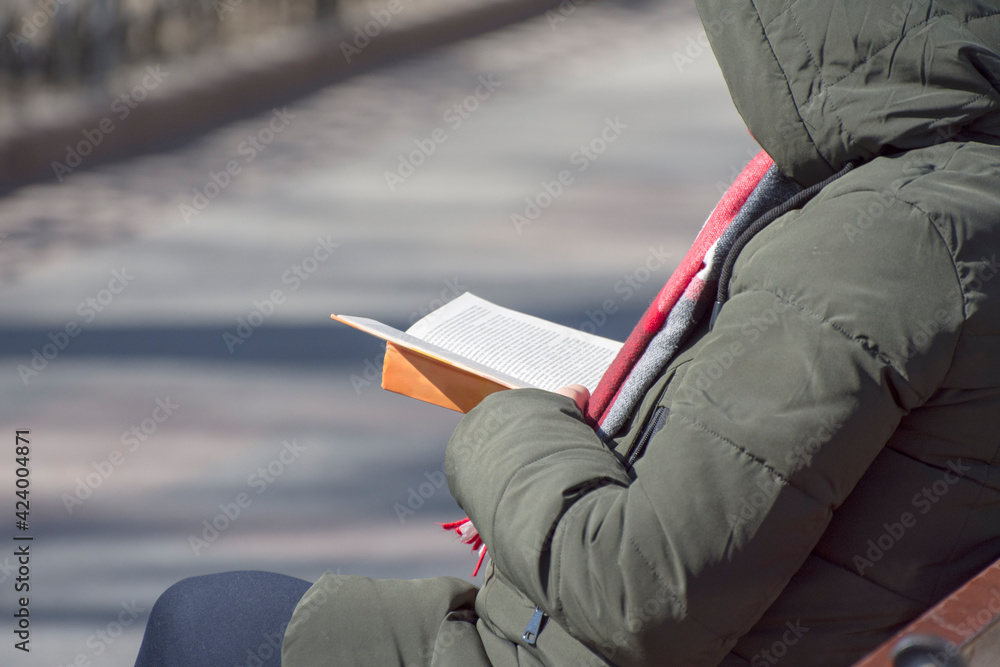 A person reads a book in a city park.