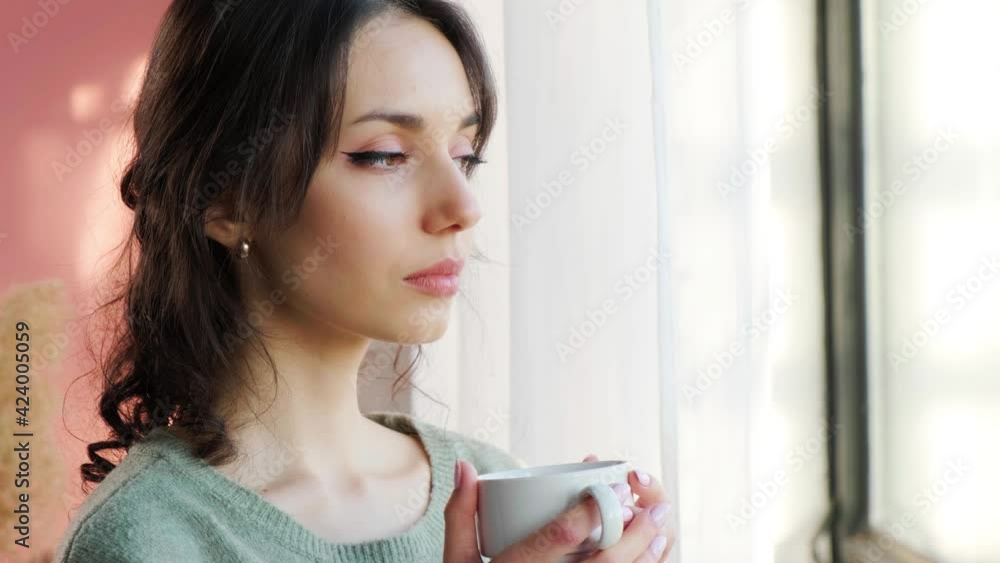 Beautiful woman sitting near window and enjoy a cupt of tea on background of sunset. Beautiful woman sitting near window and enjoy a cupt of tea on background of sunset.