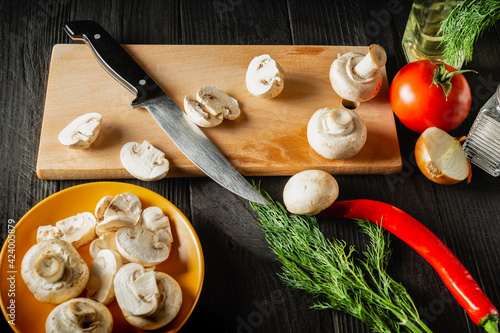 Sliced mushrooms on a cutting board and knife. Set of vegetables for cooking delicious food with mushrooms in a restaurant or cafe