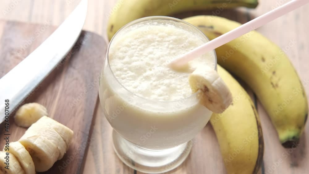 glass banana milk shake and banana on table at morning glass banana milk shake and banana on table at morning