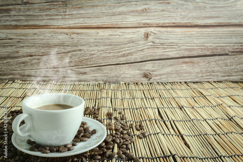 coffee cups and coffee beans with smoke on wooden background.