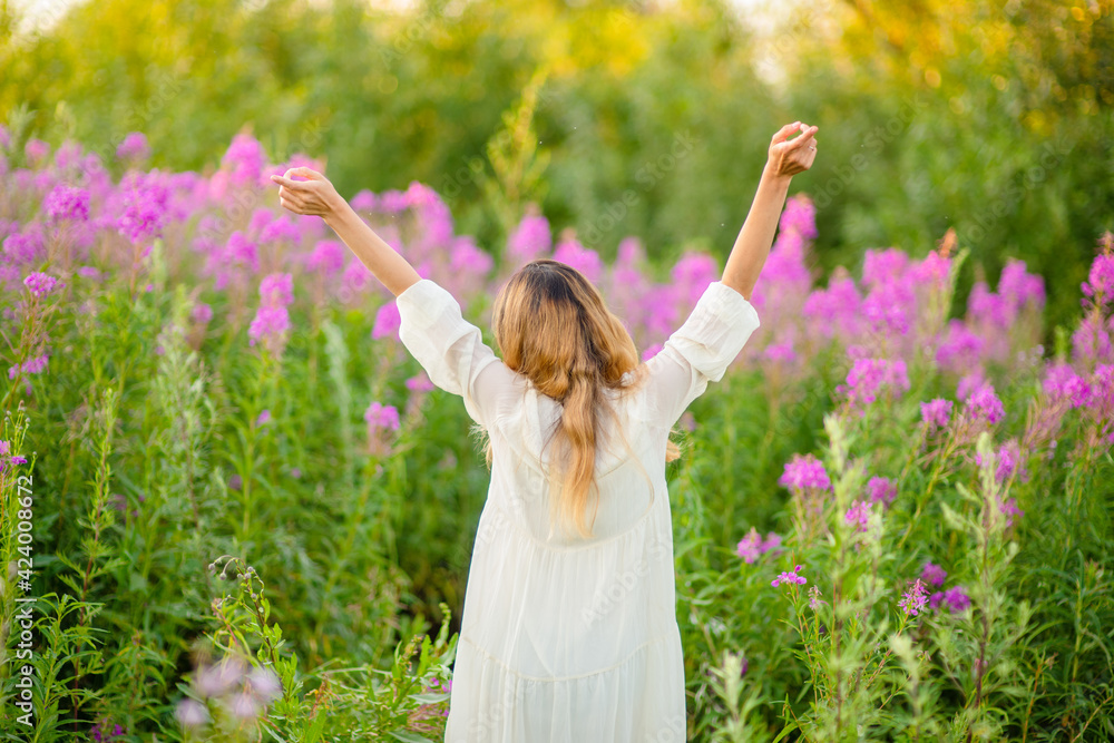 The girl stands with her back raised her hand with a bouquet of flowers on a background of greenery The girl stands with her back raised her hand with a bouquet of flowers on a background of greenery