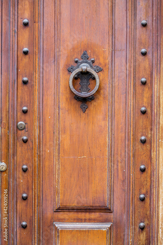 Old wooden door with iron casted round handle, a true piece of art, street view photo taken at Siena, Tuscany, Italy