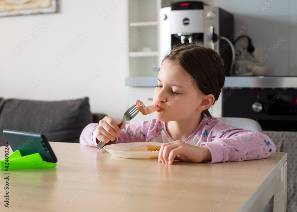 The child is having breakfast in front of the phone. Lunch with a gadget.. The child is having breakfast in front of the phone. Lunch with a gadget..