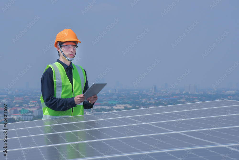 An engineer works on the inspection and maintenance of equipment at roof-mounted solar power plants of condominium buildings, houses with a tabletop in his hand. An engineer works on the inspection and maintenance of equipment at roof-mounted solar power plants of condominium buildings, houses with a tabletop in his hand.