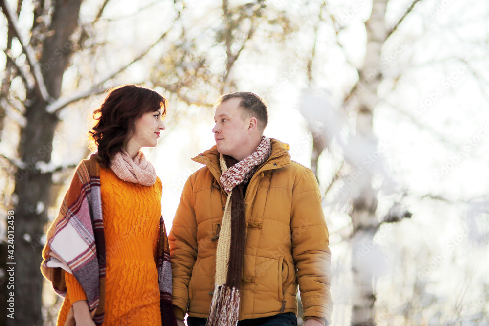 Fototapeta premium Warm winter portrait of young interracial smiling couple on a walk in the forest
