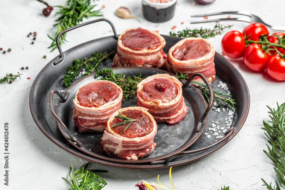 Fresh pieces pork ready to cook. Sirloin medallions steaks wrapped in bacon on old meat tray on a light background, filet Mignon. top view Fresh pieces pork ready to cook. Sirloin medallions steaks wrapped in bacon on old meat tray on a light background, filet Mignon. top view