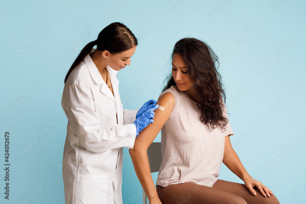 Nurse Vaccinating Lady Applying Bandage On Vaccinated Arm, Studio Shot Nurse Vaccinating Lady Applying Bandage On Vaccinated Arm, Studio Shot