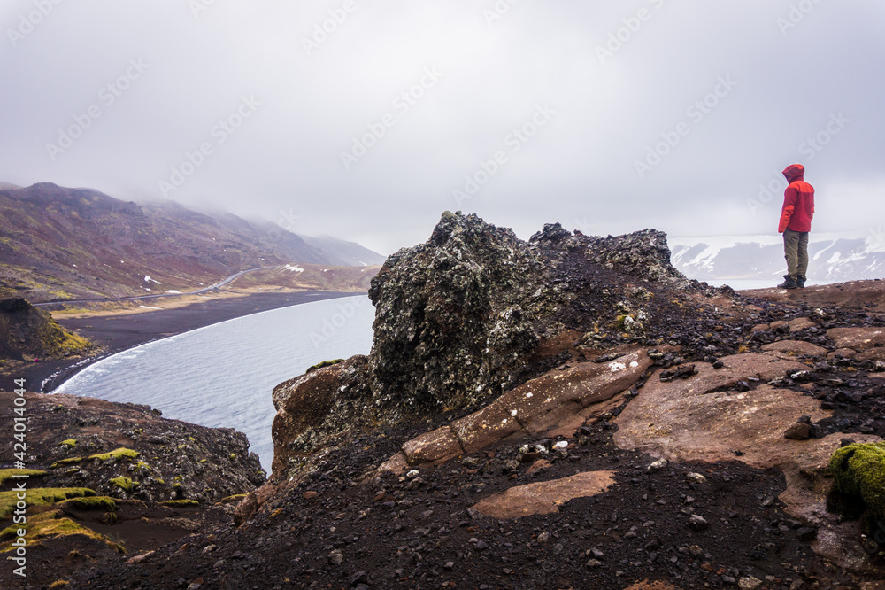 Tourist standing on a rock and looking at black beach of Lake Kleifarvatn near Krysuvik in Iceland