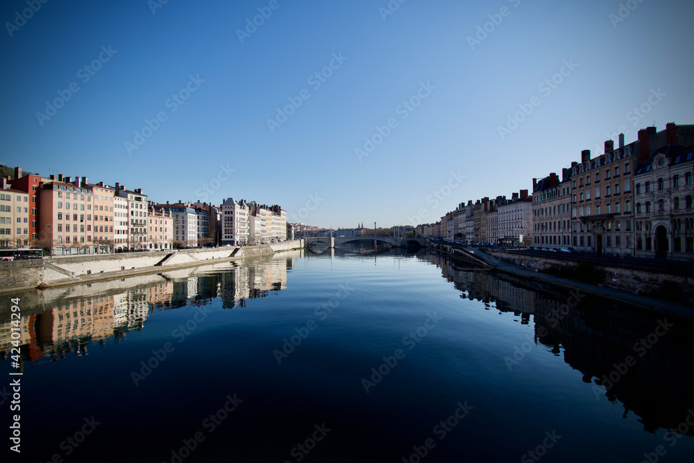 Photo of the Saône river flowing in the centre of Lyon at sunrise. It was taken from the Saint George bridge towards the Bonaparte bridge.