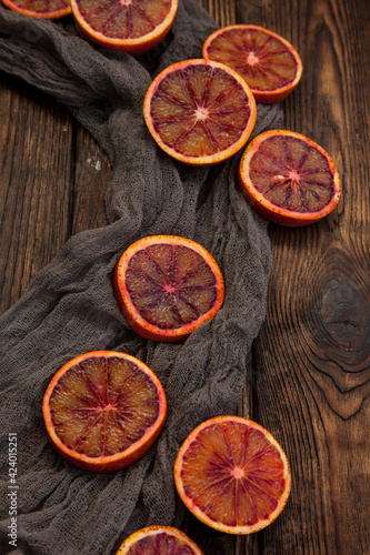 Slices of red oranges on a dark wooden background. Rustic style