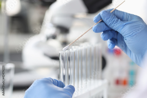 Scientist chemist inserting cotton swab into glass test tube closeup photo