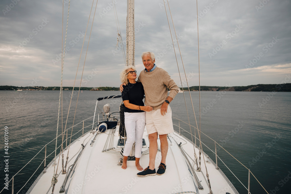Senior woman looking at man while standing on boat against sky during sunset Senior woman looking at man while standing on boat against sky during sunset