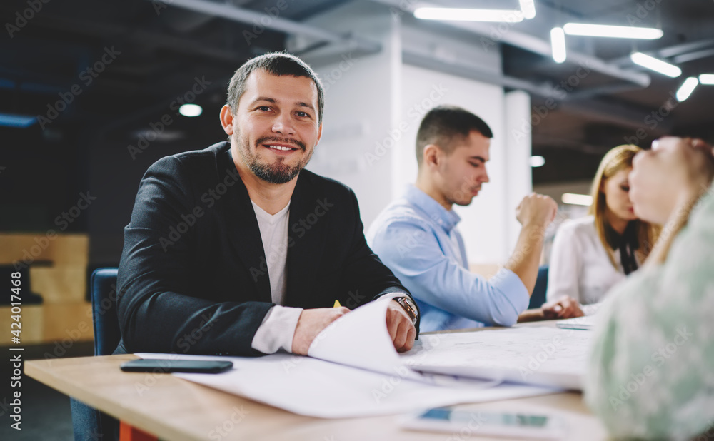 Portrait of happy Caucaisan businessman smiling at camera during collaborative meeting with professional colleagues enjoying positive brainstorming at table desktop, successful male employer Portrait of happy Caucaisan businessman smiling at camera during collaborative meeting with professional colleagues enjoying positive brainstorming at table desktop, successful male employer