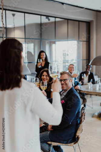 Female entrepreneur with wineglass looking at colleagues during company party