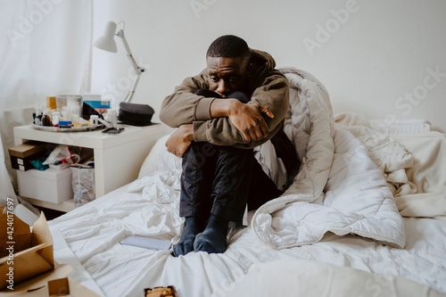 Depressed man sitting on bed at home