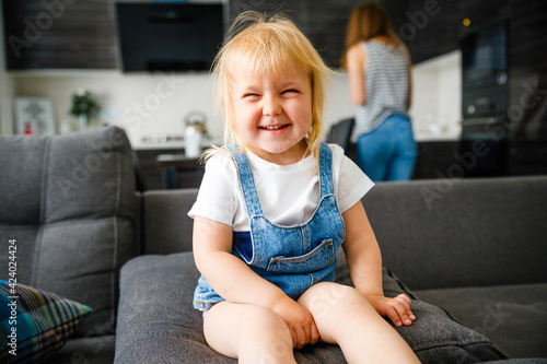 The little girl laughs next to her mother. 