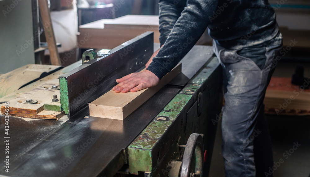 Professional carpenter milling the wood on the  huge saw for a modern furniture, joinery and woodwork concept