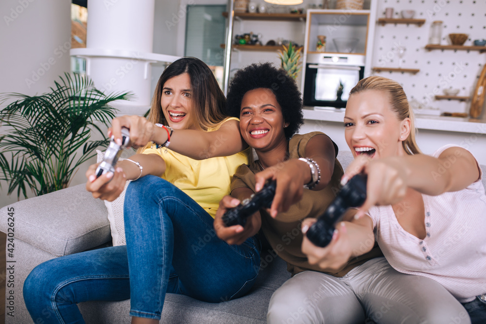 Portrait of happy women friends playing video games at home.