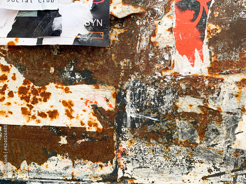 Fototapeta premium Torn poster on rust metal texture. Old grungy street wall with ripped rock concert advertisements.