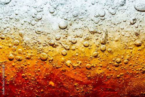 Close up view of the ice cubes in dark cola background. Texture of cooling sweet summer's drink with foam and macro bubbles on the glass wall. Fizzing or floating up to top of surface.