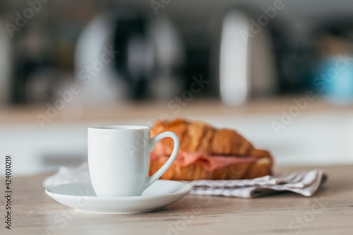breakfast of coffee and croissant sandwich stuffed with salami